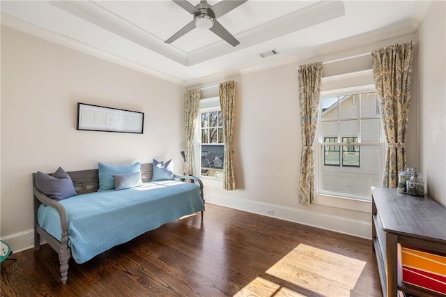 living area with dark wood-type flooring, ceiling fan, ornamental molding, and a tray ceiling