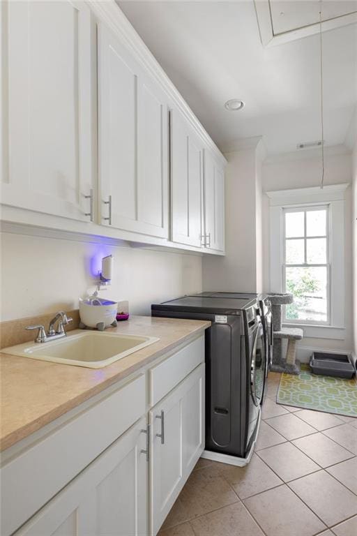 washroom with sink, light tile patterned floors, cabinets, and independent washer and dryer