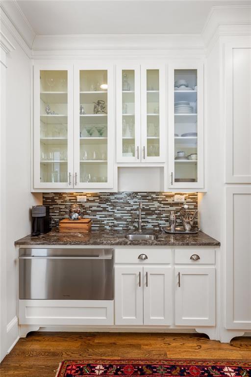 bar featuring sink, white cabinetry, backsplash, dark hardwood / wood-style flooring, and dark stone counters