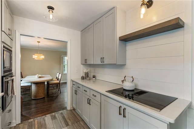 kitchen with oven, black electric cooktop, built in microwave, light countertops, and ornamental molding