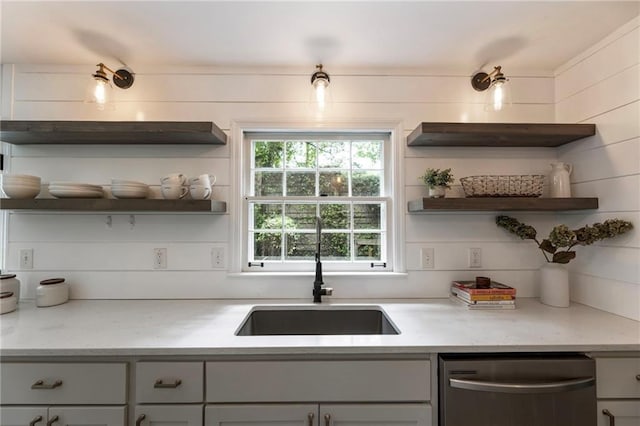 kitchen featuring open shelves, dishwasher, a sink, and light stone countertops