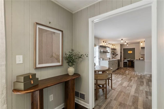 hallway featuring ornamental molding and light wood-style floors