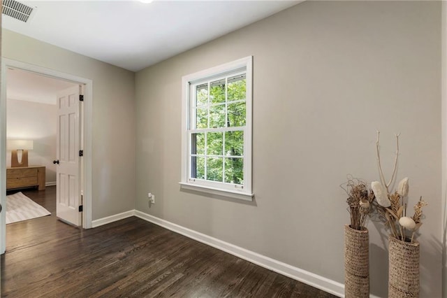 unfurnished room with baseboards and dark wood-type flooring