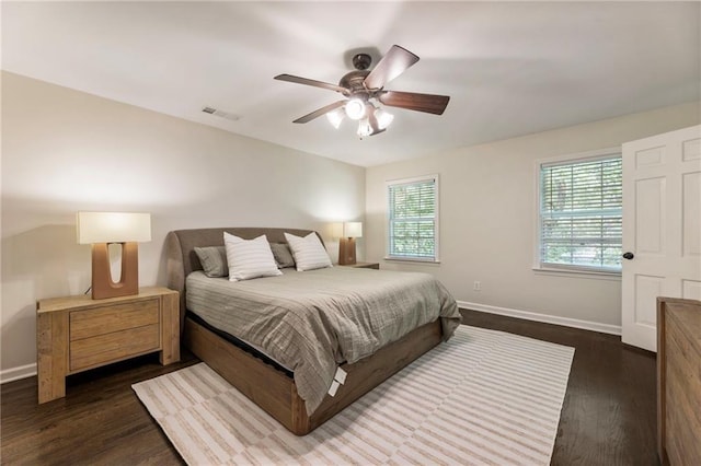 bedroom with multiple windows, baseboards, and dark wood finished floors