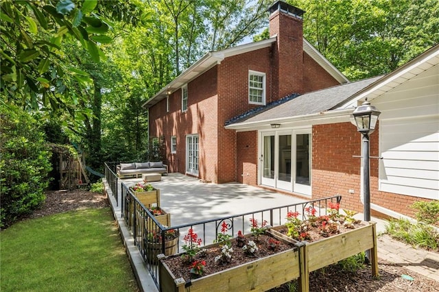 rear view of house with french doors, an outdoor hangout area, a patio, brick siding, and a chimney