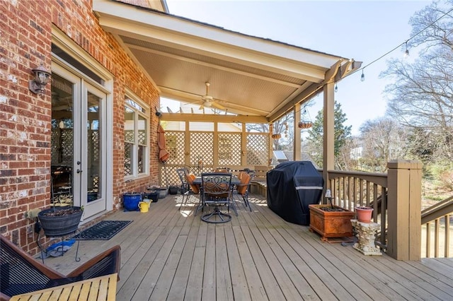 wooden deck featuring outdoor dining space, ceiling fan, and area for grilling