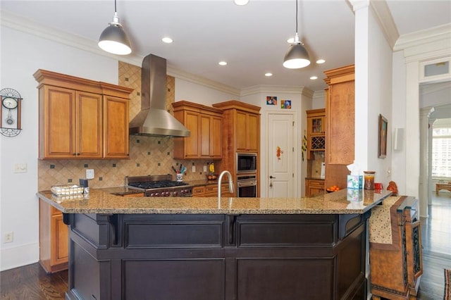 kitchen featuring appliances with stainless steel finishes, dark wood-type flooring, a peninsula, and wall chimney exhaust hood