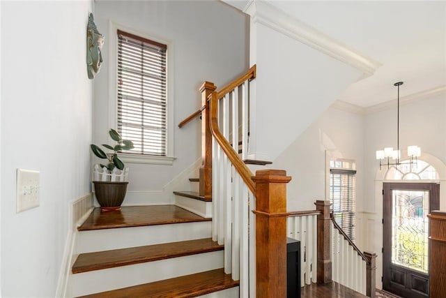 stairway with ornamental molding and a notable chandelier