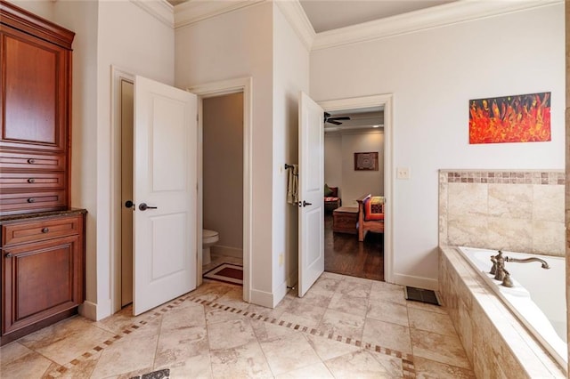 ensuite bathroom featuring ensuite bathroom, toilet, baseboards, tiled tub, and crown molding