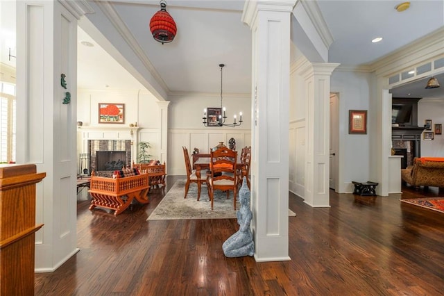 dining space featuring dark wood-style flooring, ornamental molding, a premium fireplace, and ornate columns