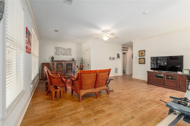 interior space featuring light wood finished floors, ceiling fan, visible vents, and crown molding