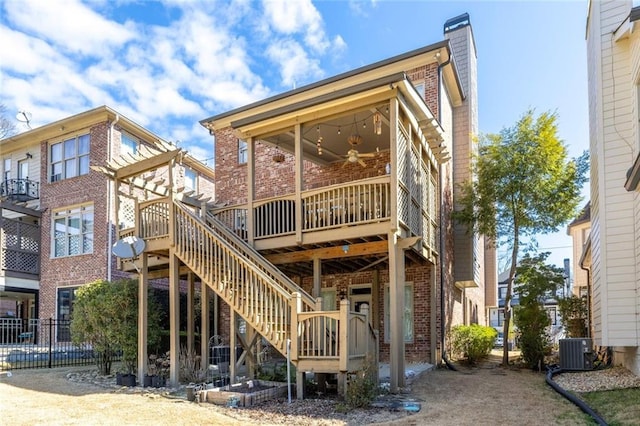 rear view of house with ceiling fan, a chimney, stairs, central AC, and brick siding