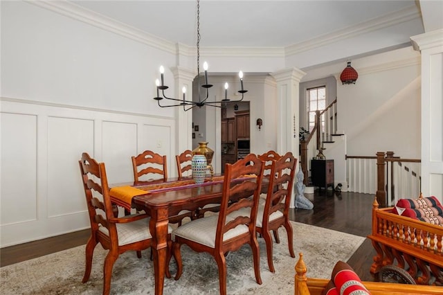 dining area with ornamental molding, dark wood finished floors, decorative columns, and a decorative wall