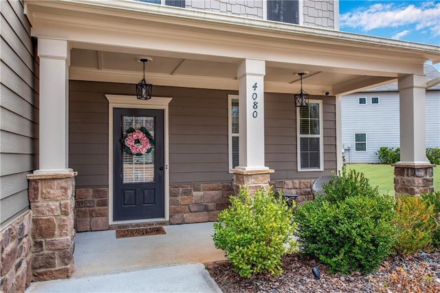 doorway to property featuring stone siding and covered porch