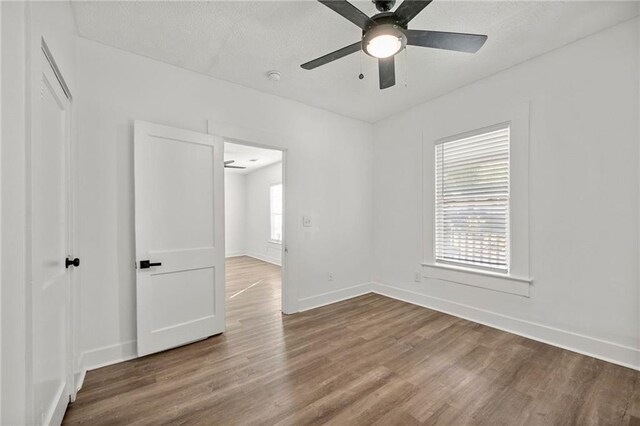 empty room with hardwood / wood-style floors, ceiling fan, and a textured ceiling