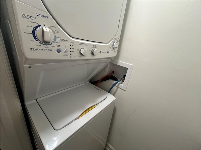 clothes washing area featuring stacked washer / dryer and laundry area