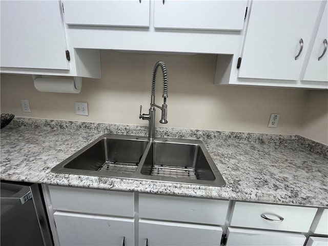 kitchen featuring dishwashing machine, a sink, and white cabinets