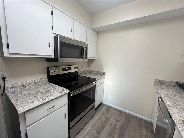 kitchen with baseboards, appliances with stainless steel finishes, wood finished floors, light countertops, and white cabinetry