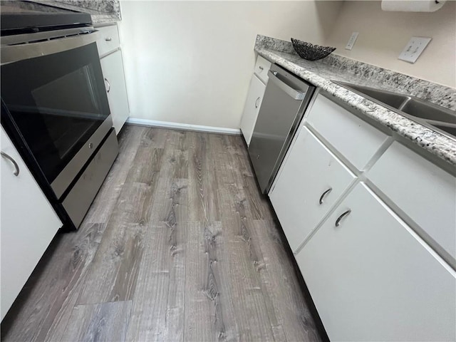 kitchen featuring stainless steel appliances, light countertops, white cabinetry, and wood finished floors