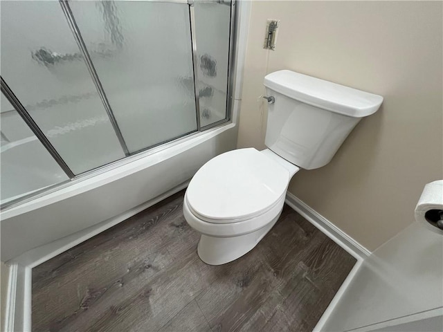 bathroom with shower / bath combination with glass door, wood finished floors, toilet, and baseboards