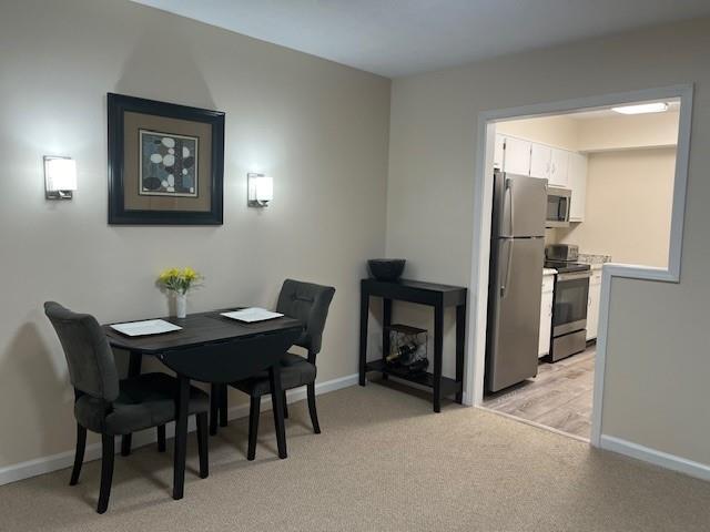 dining area featuring baseboards and light colored carpet