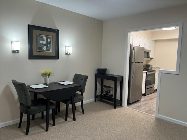 dining space with light colored carpet and baseboards