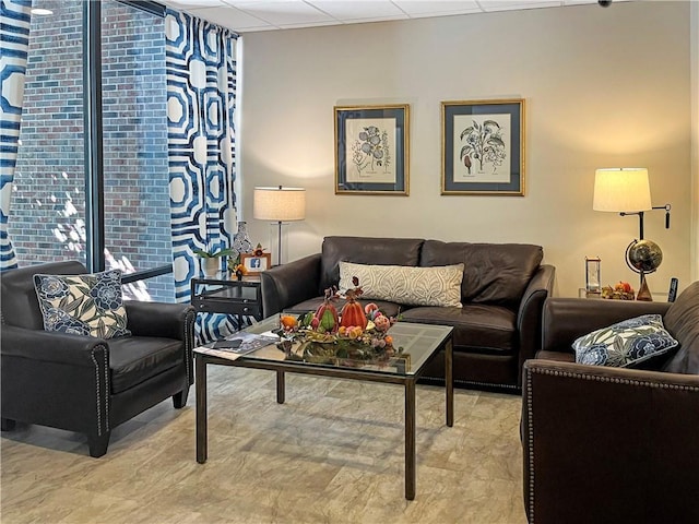 living room with floor to ceiling windows and a drop ceiling