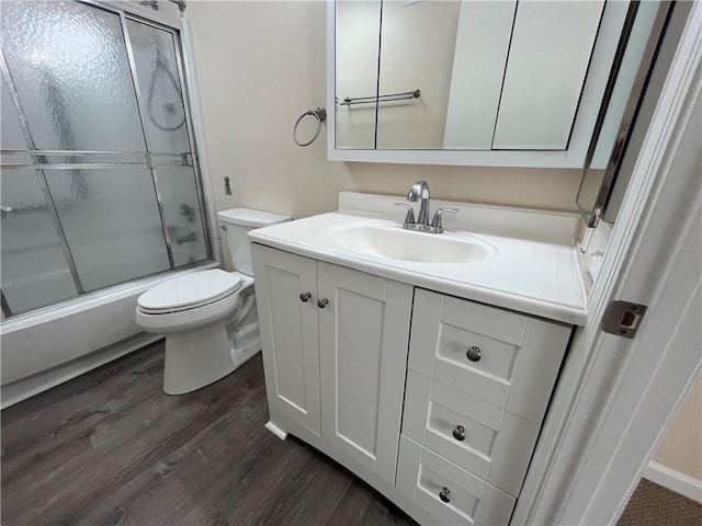 full bath featuring bath / shower combo with glass door, vanity, toilet, and wood finished floors