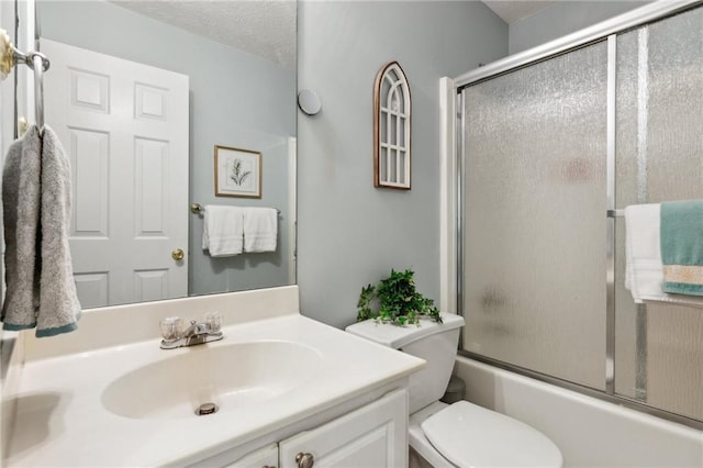 bathroom with vanity, combined bath / shower with glass door, toilet, and a textured ceiling