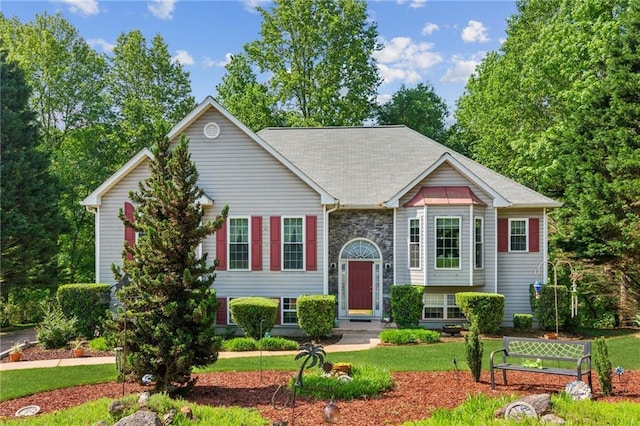 raised ranch featuring stone siding and a front yard