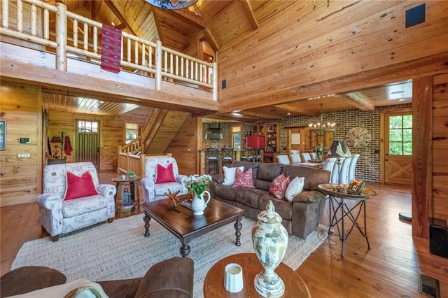 living room featuring an inviting chandelier, hardwood / wood-style flooring, wooden walls, beam ceiling, and wood ceiling