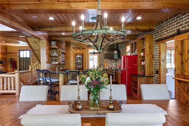 dining room featuring hardwood / wood-style floors, beam ceiling, wood walls, and brick wall