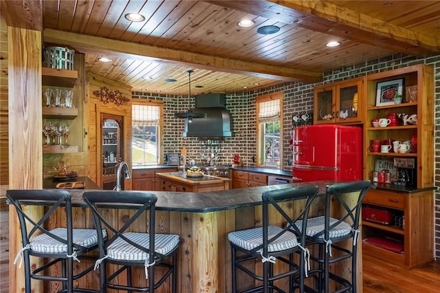 bar featuring hardwood / wood-style floors, high end fridge, brick wall, wall chimney exhaust hood, and wooden ceiling