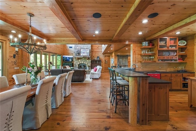 dining space with beam ceiling, light hardwood / wood-style flooring, wood walls, and wood ceiling