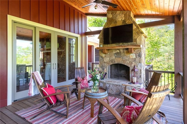 wooden deck with a stone fireplace, french doors, and ceiling fan