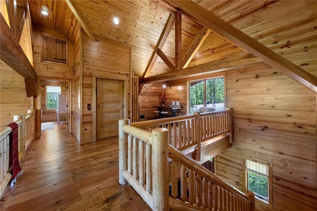 hallway featuring beamed ceiling, high vaulted ceiling, wood walls, hardwood / wood-style flooring, and wooden ceiling