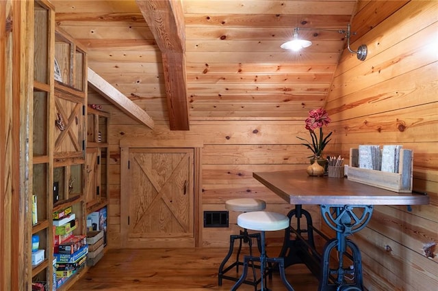 dining area with wood walls, hardwood / wood-style flooring, wood ceiling, and lofted ceiling