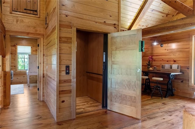 corridor with lofted ceiling with beams, wood ceiling, wood walls, and light hardwood / wood-style flooring