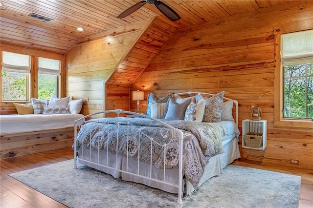 bedroom with ceiling fan, wood-type flooring, wooden walls, lofted ceiling, and wooden ceiling