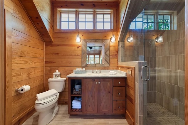 bathroom featuring a healthy amount of sunlight, wooden walls, oversized vanity, and toilet