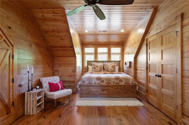 bedroom with lofted ceiling, wood ceiling, wood walls, and hardwood / wood-style floors