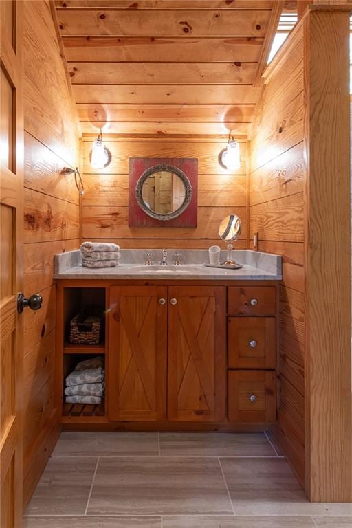 bathroom featuring lofted ceiling, vanity, and wood walls