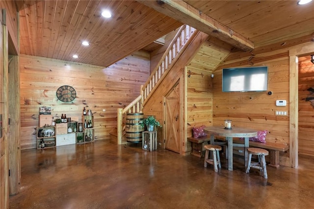 dining room with wood ceiling, concrete floors, lofted ceiling with beams, and wooden walls