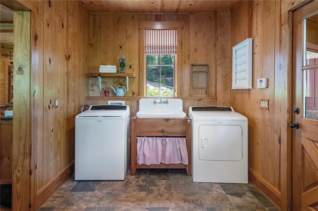 washroom with washer and dryer, wood walls, sink, wood ceiling, and dark tile floors