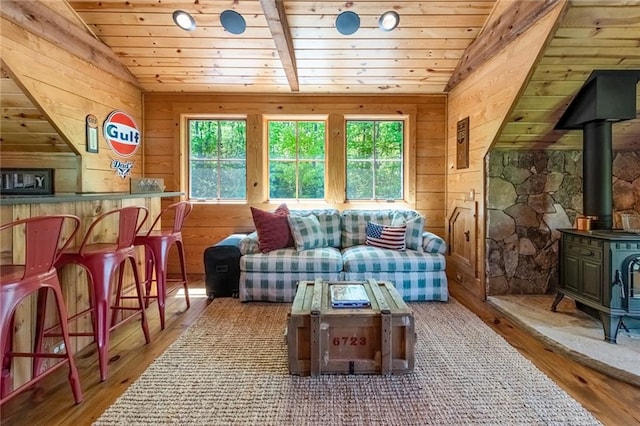 living room with vaulted ceiling, hardwood / wood-style flooring, and a wood stove