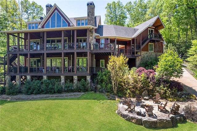 rear view of house featuring a patio, a balcony, an outdoor fire pit, and a lawn