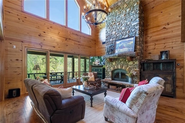 living room with wooden walls, a towering ceiling, an inviting chandelier, and wood-type flooring