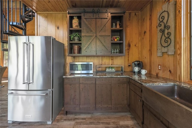 kitchen featuring stainless steel appliances, wooden ceiling, hardwood / wood-style floors, and wooden walls