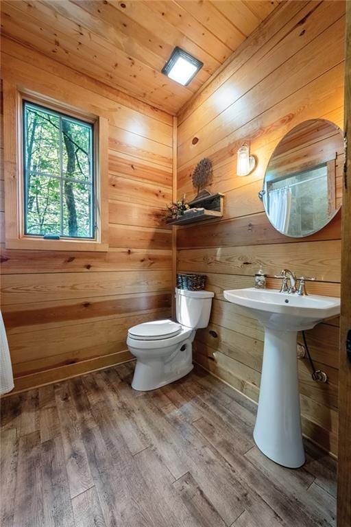 bathroom featuring wood-type flooring, wooden walls, and toilet