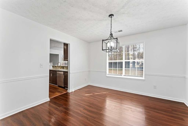 unfurnished dining area featuring dark wood-style floors, visible vents, a sink, a textured ceiling, and a chandelier